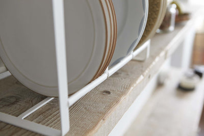 Close look at Yamazaki's white dish rack holding dishes on a kitchen shelf.