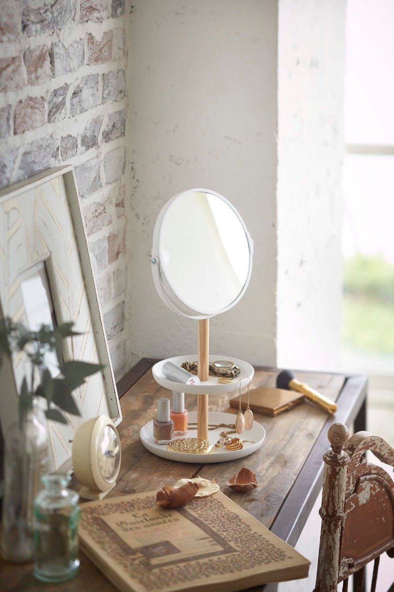 Yamazaki's Tabletop round mirror with tiered trays holding accessories on a dresser.