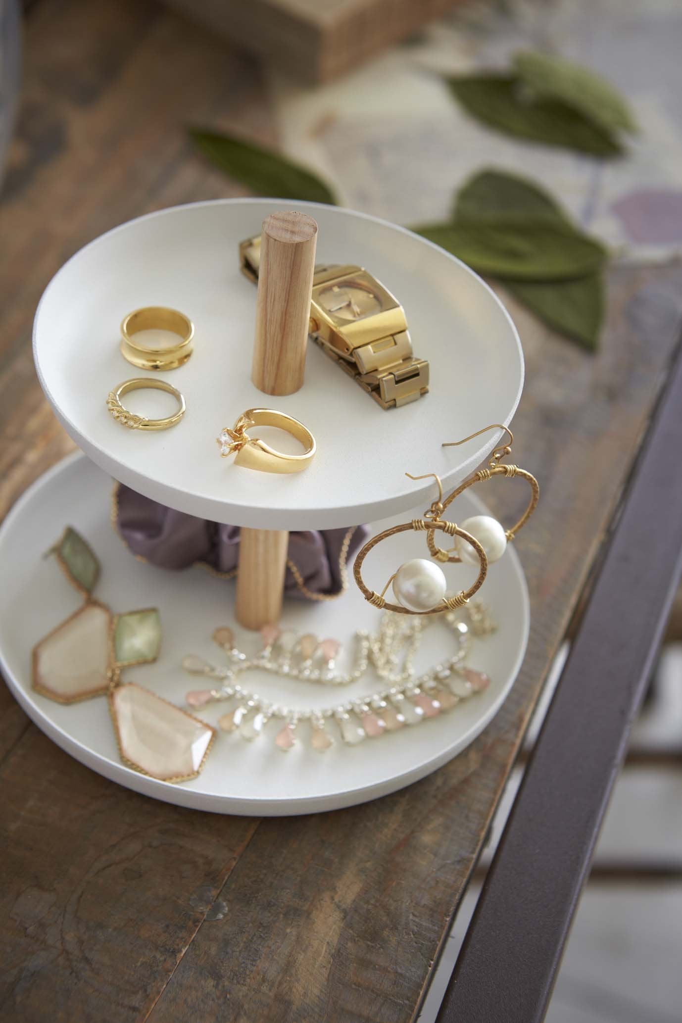 A tiered accessory tray by Yamazaki filled with accessories sitting on a desk.