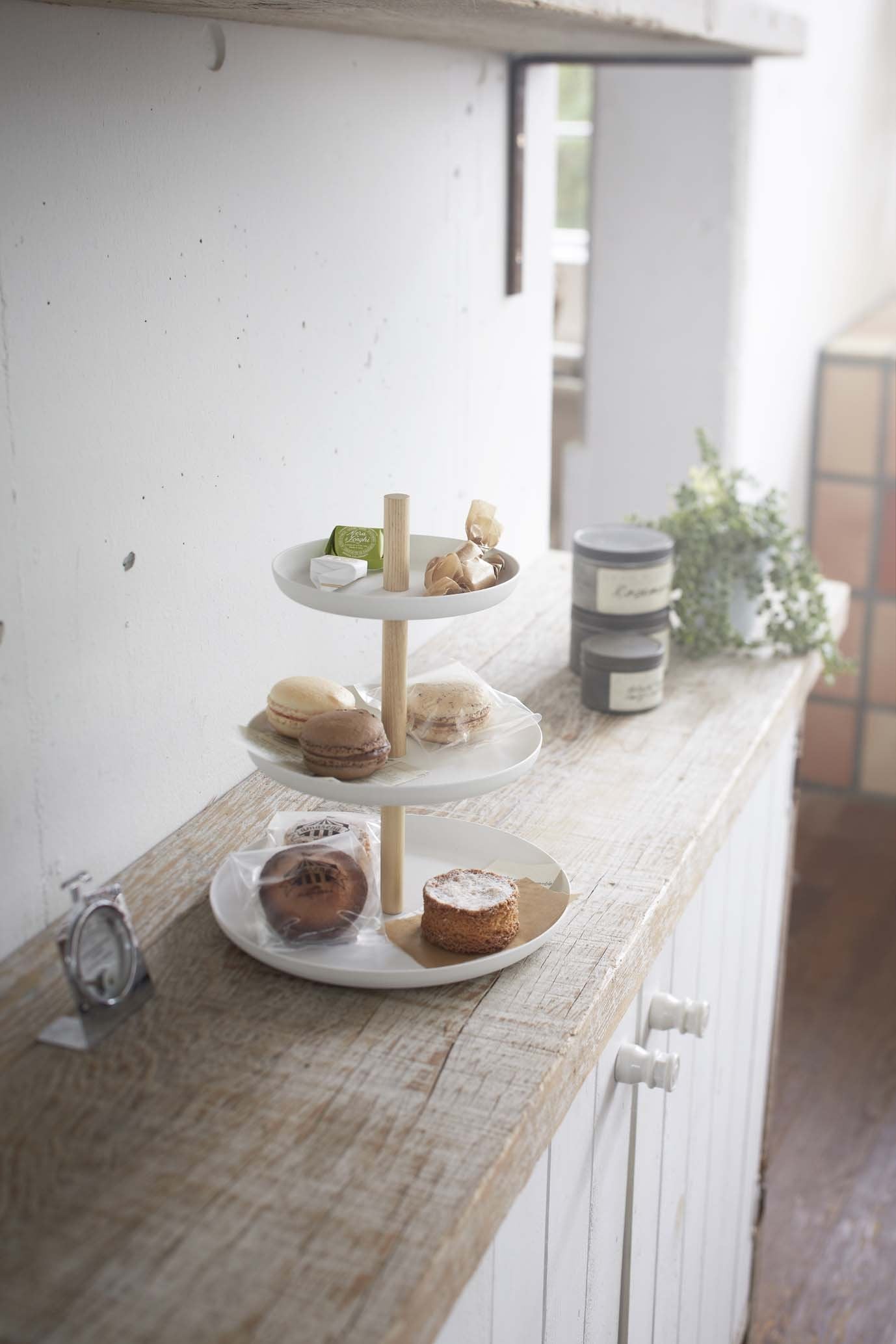 Three-tier Yamazaki tabletop server set with pastries on a kitchen shelf.