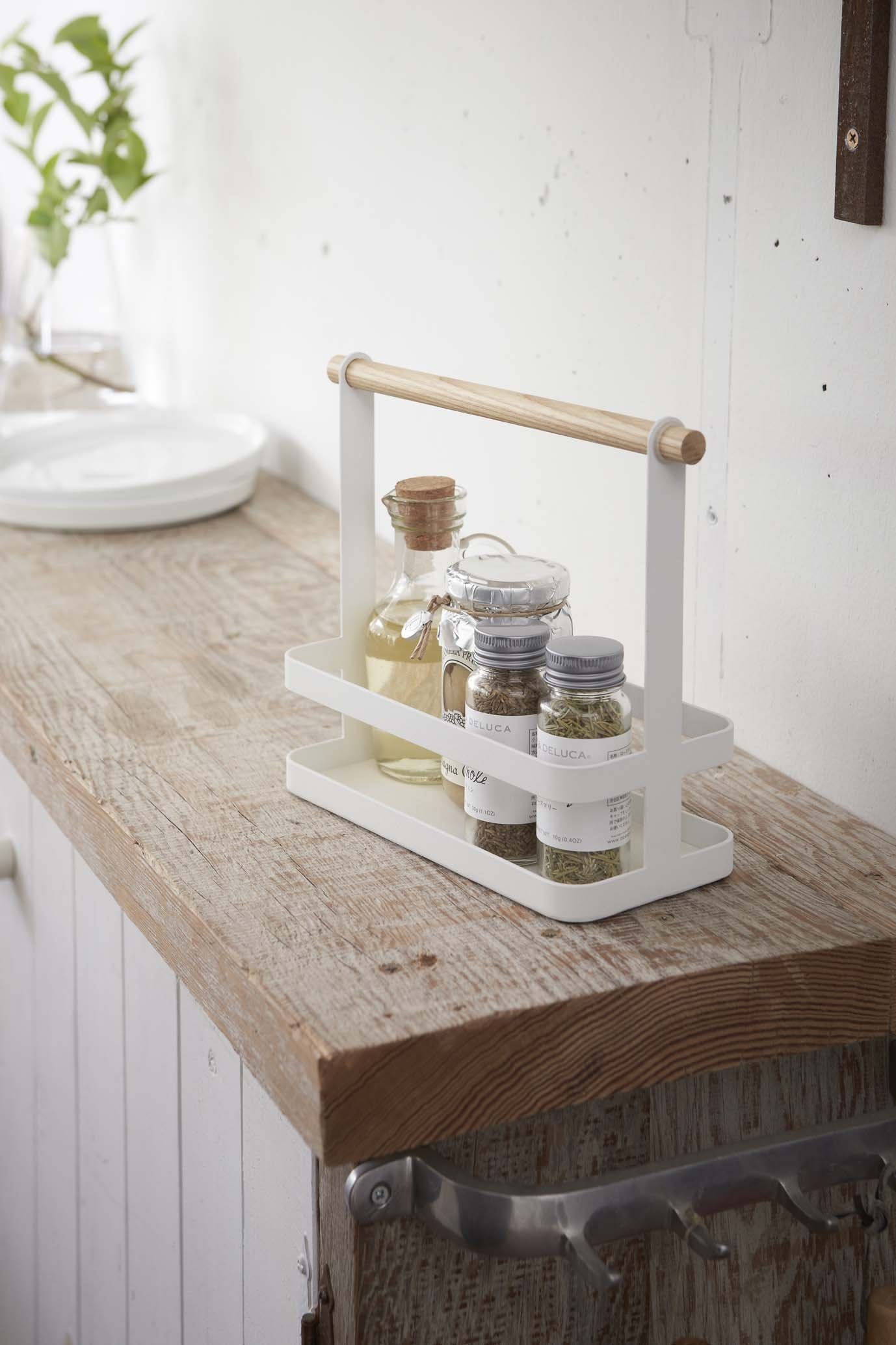 White metal spice rack holding spice canisters on a kitchen countertop