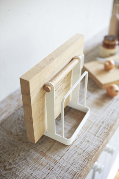 Angled view of Yamazaki Cutting Board Stand on countertop, holding a wooden cutting board