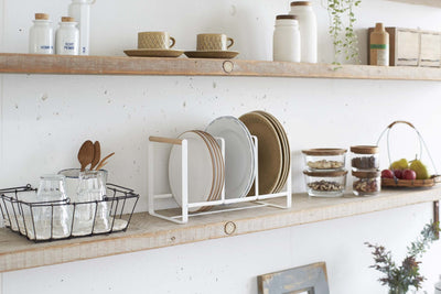 Yamazaki's white dish rack with wooden handles holding dishes on a kitchen shelf
