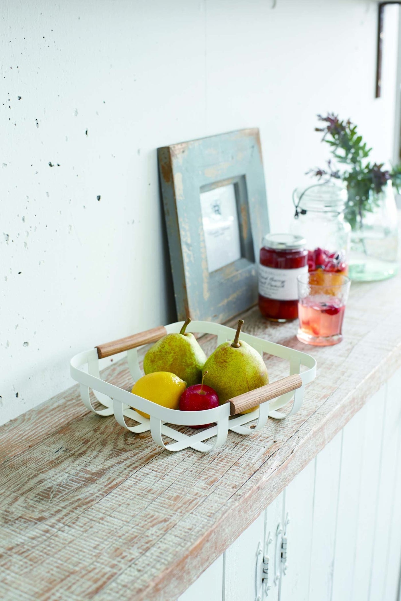 White basket by Yamazaki holding fruit on kitchen shelf