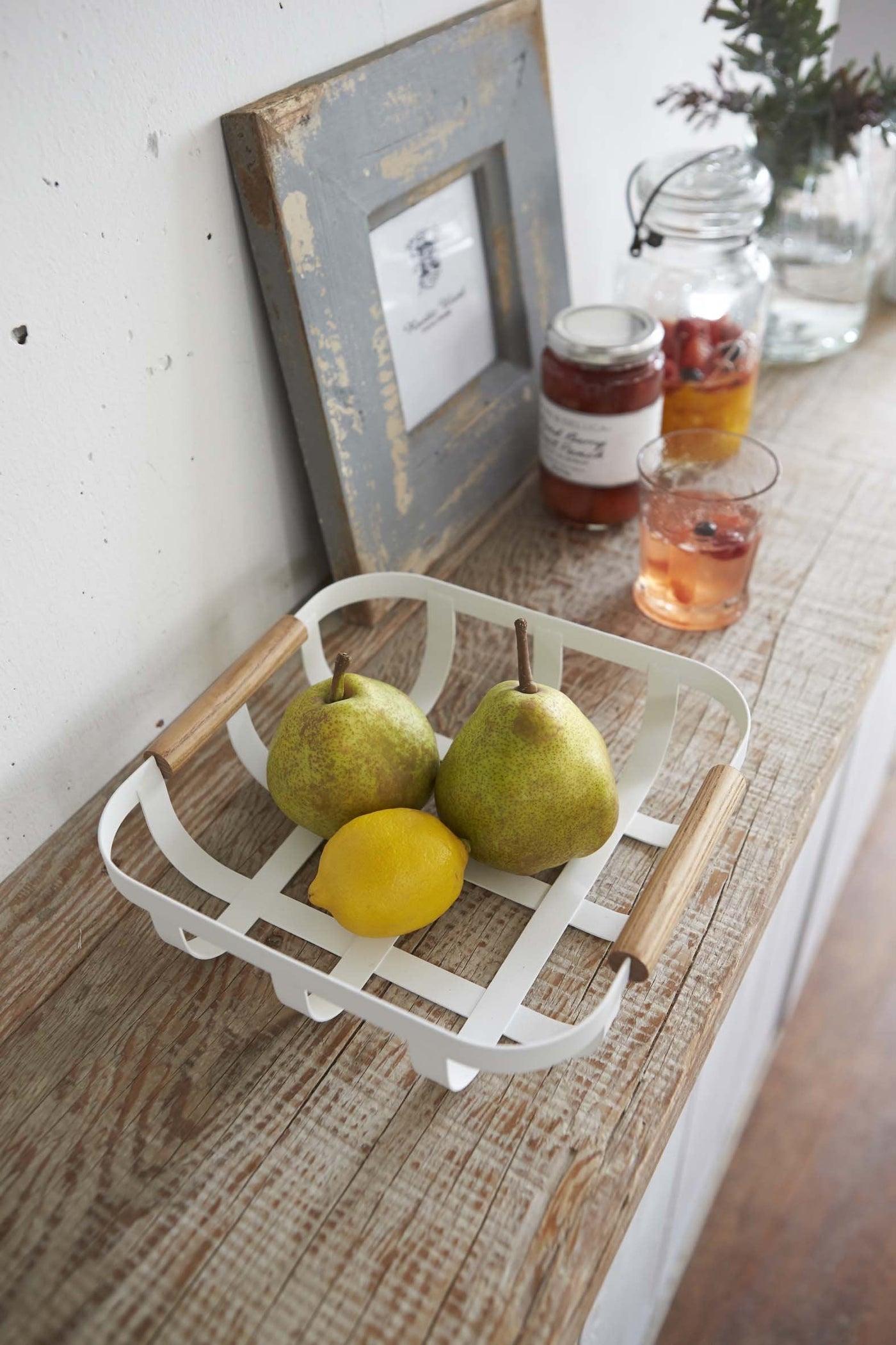 White basket by Yamazaki holding fruit on kitchen shelf