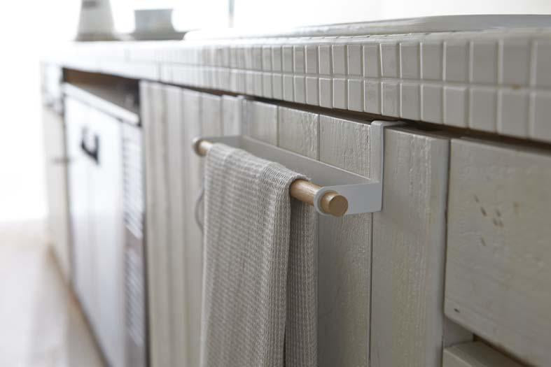 Yamazaki's wooden towel bar with white metal hooks hanging over bathroom cabinet door, holding a towel