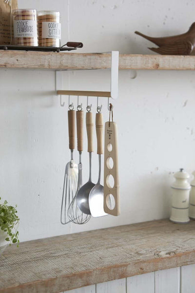Yamazaki rod holding utensils suspended under a kitchen shelf.
