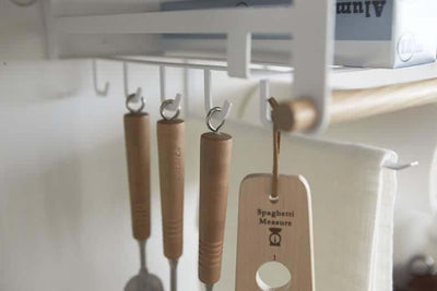 Yamazaki rack hanging from kitchen shelf holding utensils