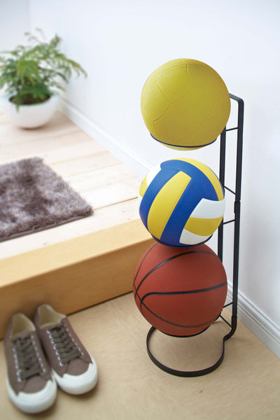 Yamazaki's vertical stand with wire racks holding yellow and blue balls and a basketball, positioned in a room next to shoes